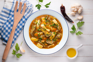 Squid stew with potatoes, artichokes and vegetables. Top view table with  decoration.