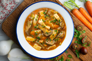Squid stew with potatoes, artichokes and vegetables. Top view table with  decoration.
