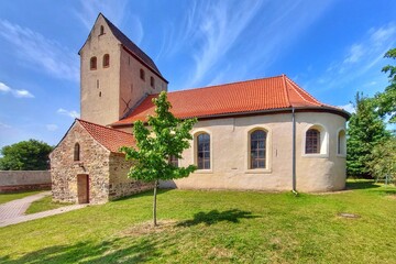 Church St. Peter with tree and grassy surroundings under a clear sky in Ochtmersleben, Germany