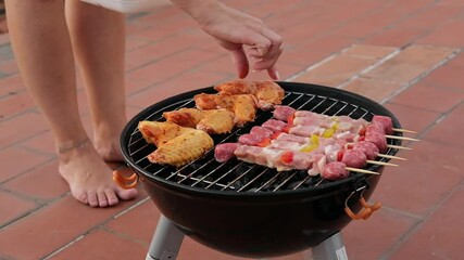 woman cooking grilling sweet corn and meat kebabs and chicken wings on the home terrace on a charcoal grill, Barbecue Grill - Powered by Adobe