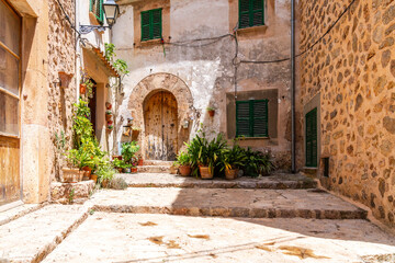 Verschiedene Pflanzen in Töpfen in einer Straße Ecke in einem Dorf, die an der Hauswand stehen auf der Treppe in Mallorca, Spanien