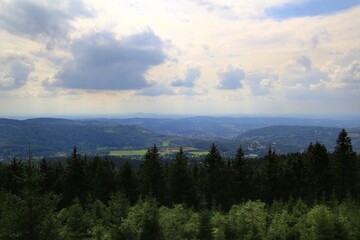 Scenic mountain landscape overlooking the dense Thuringian forest, distant valleys, and a vast sky filled with clouds