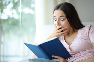 Fototapeta premium Surprised woman reading paper book in a house