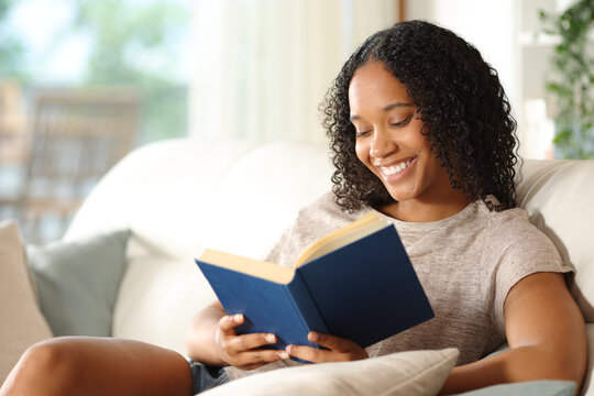 Happy black reader reading a book at home