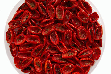 Tomatoes, dried in small pieces, lie in a plate on a white background.