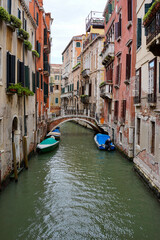 A colorful Venetian canal with boats lining the water and vibrant, old buildings on either side. Ideal for travel imagery, cityscape collections, or promoting Italian culture.