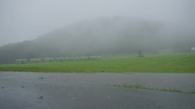 Pan wide shot of heavy rain and flooded field and road