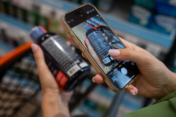 Customer scanning a product's barcode with a smartphone while shopping in a supermarket. The action highlights modern technology enhancing the retail experience
