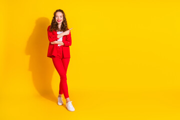 Full size photo of pretty young woman direct finger empty space wear red suit isolated on yellow color background