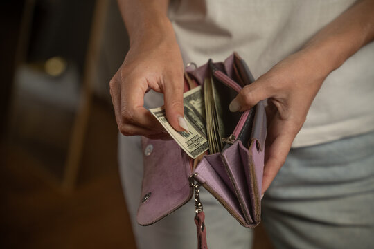 Woman opens a pink wallet, revealing banknotes. The scene captures the act of handling cash, emphasizing personal finance and everyday transactions in a stylish setting