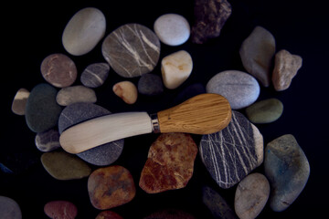 fish and cheese knife with a wooden handle on a black background with sea pebbles