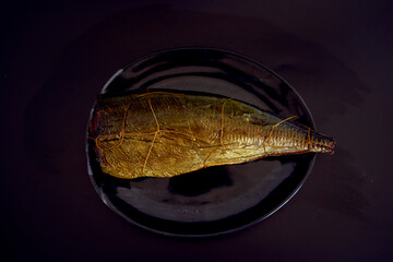 appetizing hot smoked golden horse mackerel on a black background