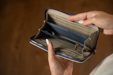 Woman showcases an empty wallet, revealing all compartments. The display highlights the lack of...