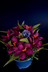  amethyst ring and a pendant of paper flowers in a blue vase on a black background