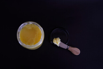 butter ghee in a transparent jar with homemade bread on a black background