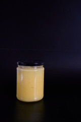 butter ghee in a transparent jar with homemade bread on a black background