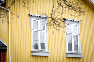 White old wooden windows with green shutters on yellow house facade,Background concept,