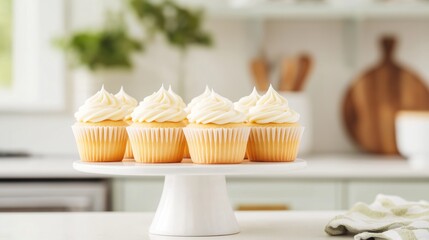 Freshly baked vanilla cupcakes with creamy frosting on a stand in a bright kitchen background.