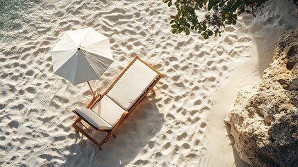 An overhead view of a chaise lounge and umbrella set on an empty, sunlit beach. The lounge chair leaves imprints in the soft sand, and the shadow of the umbrella adds contrast to the scene.