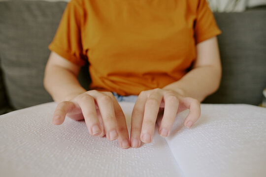 Unrecognizable female hands touching white page with Braille tactile system