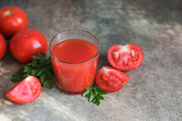 Glass of homemade tomato juice and fresh tomatoes on the table