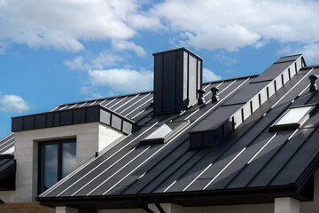 Close-up house retro roof panel with standing seam and fasteners. Modern galvanized steel roofing sheet with ribs. Classic style black metal panel with rebate joint. Falz roofing. Building's covering