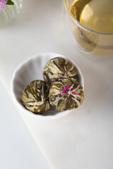 Close up handcrafted blooming tea flowers ball. Exotic asian Jasmin green tea. Vertical