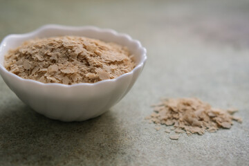 Deactivated nutritional yeast in a white bowl. Lactose-free cheese substitute