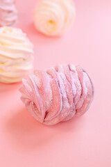 Pink marshmallow on a pink background with a sprinkle of powdered sugar. Meringue. Marshmallow.