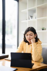 education, online, studying, E learning, young Asian woman having video call on her computer at home. Girl reading book preparing exam test having online consultation, education and learning concept.