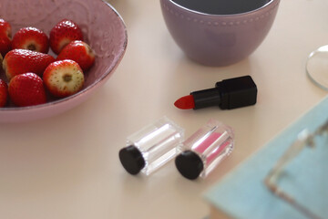 Plate of pastel macarons, cookies and chocolate, cup of tea of coffee, glass of bubble water, various berries, books and accessories on the table. Selective focus, pastel colors.