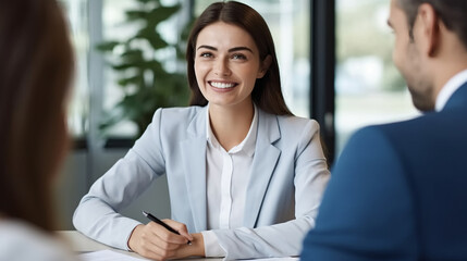 Fototapeta premium A young woman in professional attire, smiling and sitting at the table with two men during an interview for a job application.