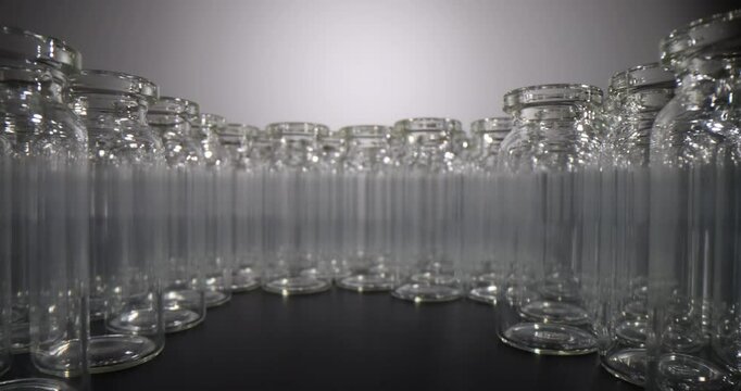 Empty glass vials for vaccines on dark background. Production of glass vials for medicine