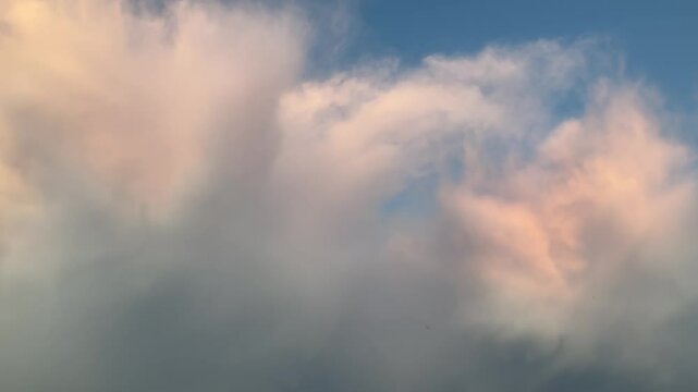 Blue sky with stormy menacing Anvil cloud, Cumulonimbus incus illuminated in orange by sunlight at the evening - shot with camera movement. Topics: storm alert, meteorology, weather, nature, climate