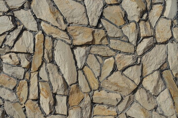 Surface of wall made of beige natural shape fieldstones