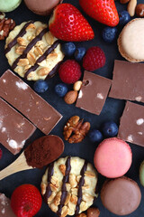 Macarons, chocolate, cookies, berries and various nuts on dark blue background. Top view.