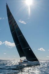 Segelyacht auf der Kreuz im Gegenlicht mit schwarzen Segeln