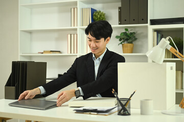 Fototapeta premium Handsome young businessman in formal suit working with laptop at office
