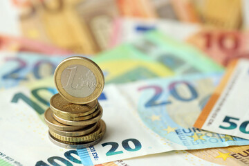 One euro coin lies on huge amount of different euro dollars banknotes