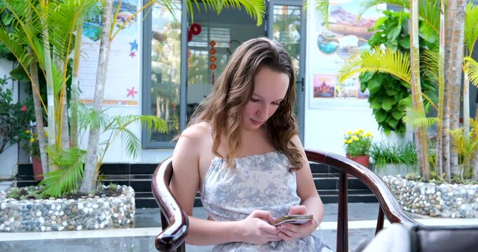 girl with phone in tropical country could I am a European girl woman typing on the phone Sitting in an expensive hotel on the street near a palm tree