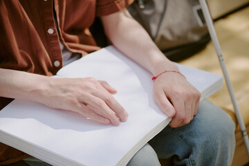 Obraz premium Medium close up of unrecognizable male hands touching page with Braille writing system