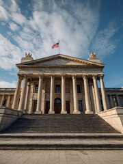 Obraz premium a grand neoclassical government building with imposing marble columns, a triangular pediment, and wide stone steps leading to its entrance