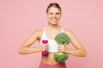 Young strong sporty cool woman wear white top casual clothes hold in hand broccoli, dumbbell isolated on plain pastel light pink background Proper nutrition healthy fast food unhealthy choice concept