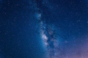 A breathtaking view of the Milky Way stretching across the night sky above a calm sea. The starry band of our galaxy is visible in all its glory. Suao, Yilan County, Taiwan.