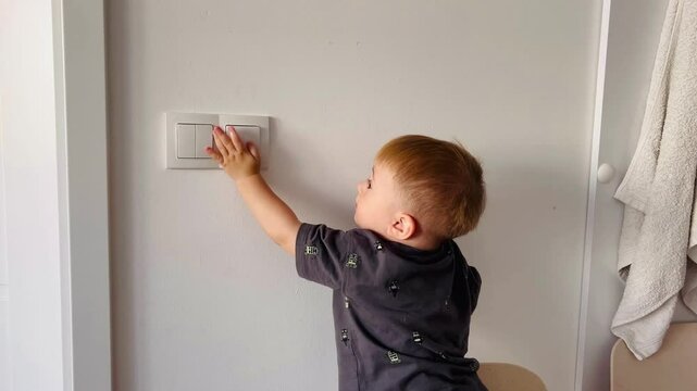 A small child turns the light on and off