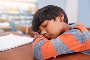 Burnout, school and sleeping with boy student in classroom at desk for child development or learning. Exhausted, fatigue and tired with learner kid at table in class for education, relax or study