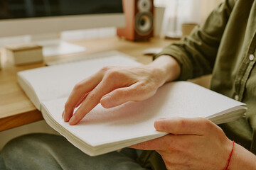 Medium close up of unrecognizable male hand touching dots on page book