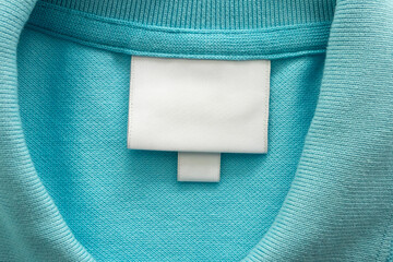 White blank laundry care clothes label on blue shirt fabric background