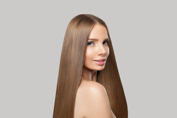 Fototapeta premium Nice woman face. Model with long brown hair and make-up on grey background. Beauty, hair care and cosmetic portrait