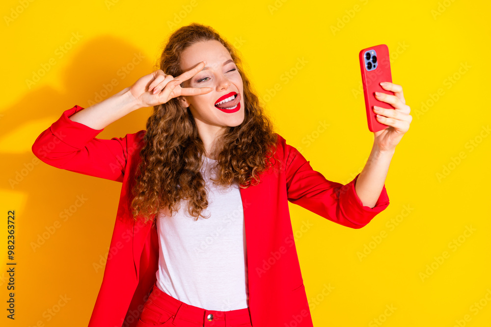 Poster Photo of pretty young woman selfie eye wink show tongue v-sign wear red suit isolated on yellow color background